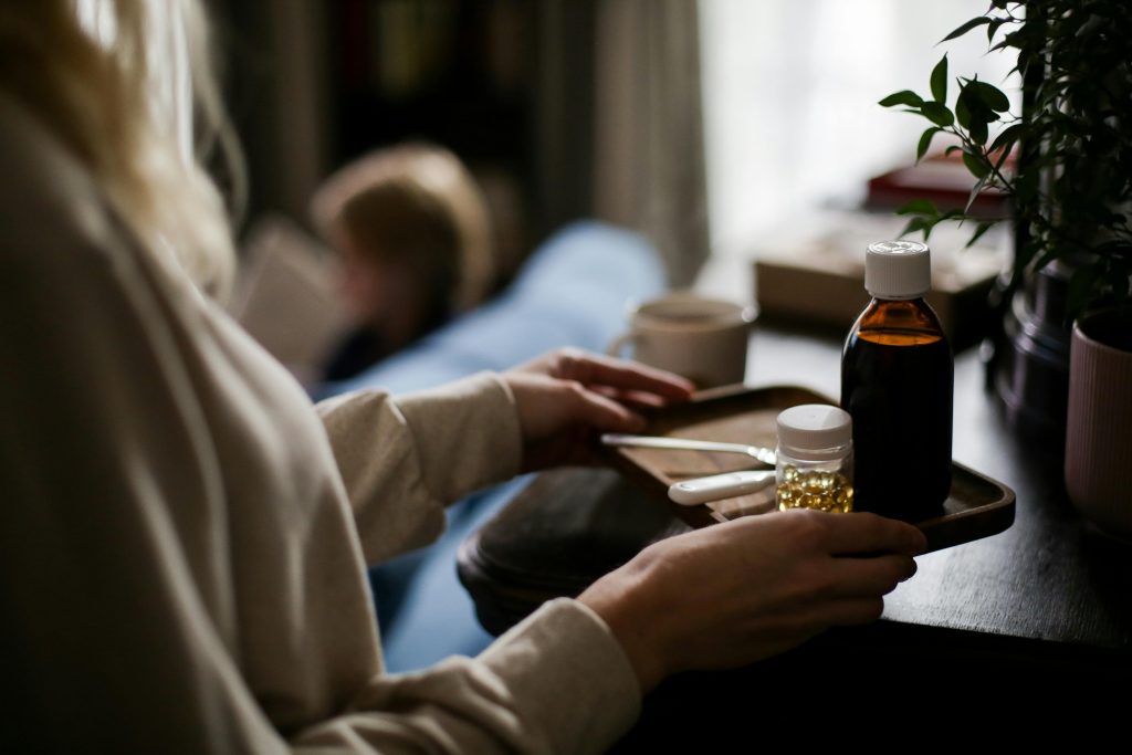 A woman looking at a bottle of cough syrup on a tray wondering why people do people abuse cough syrup.